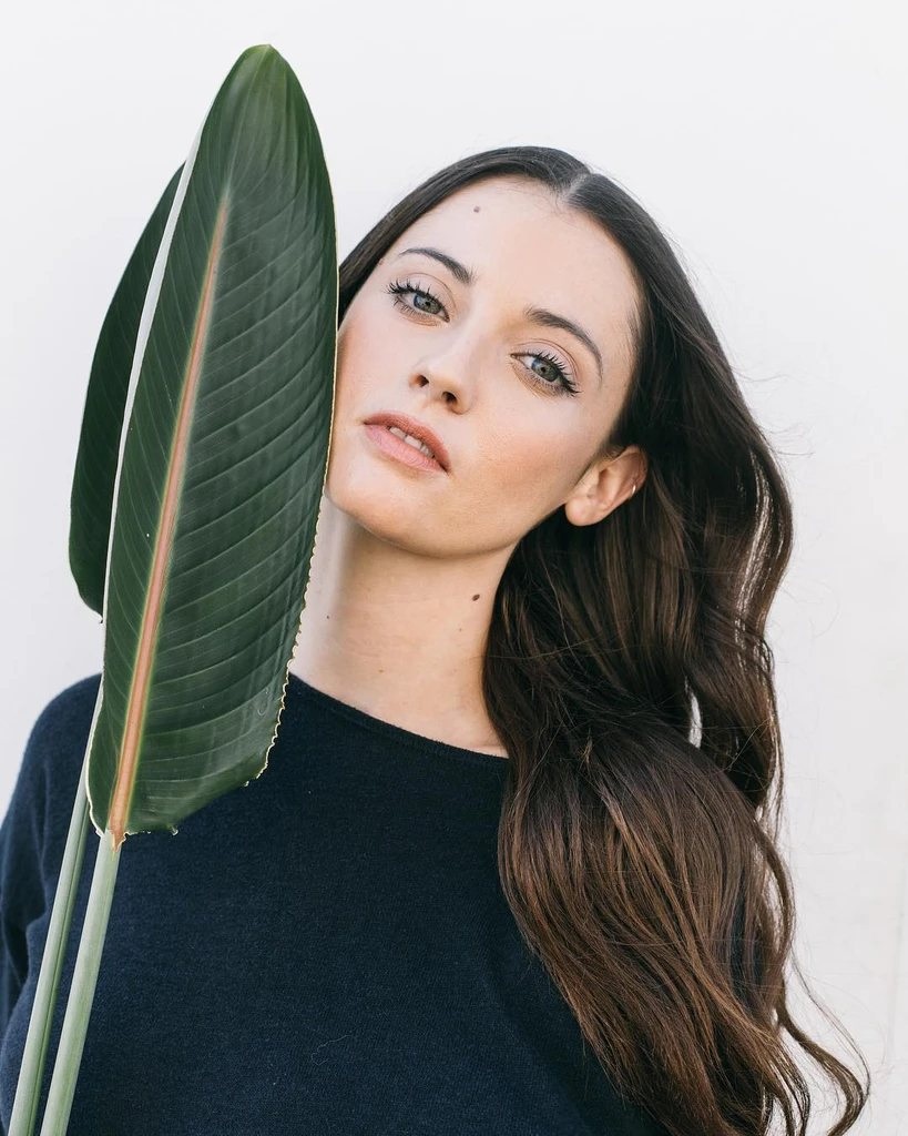 A woman who uses hyaluronic acid holding a leaf to her face