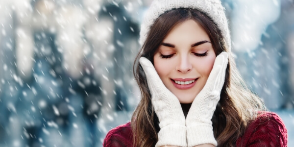 A woman touching her face with her hands during the Winter.